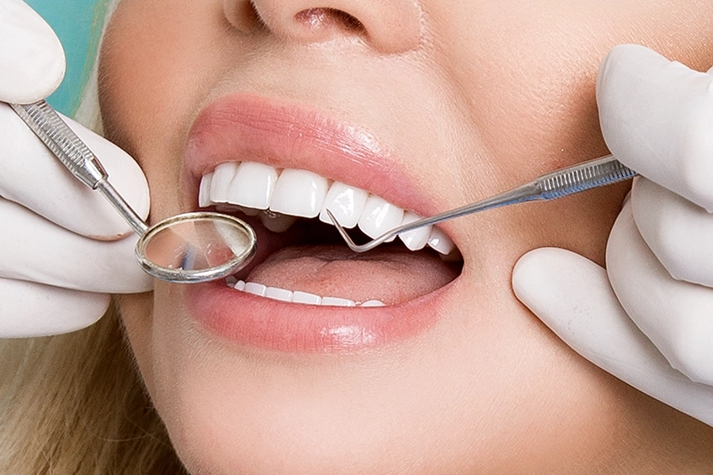 close up of woman's mouth with dentist tools