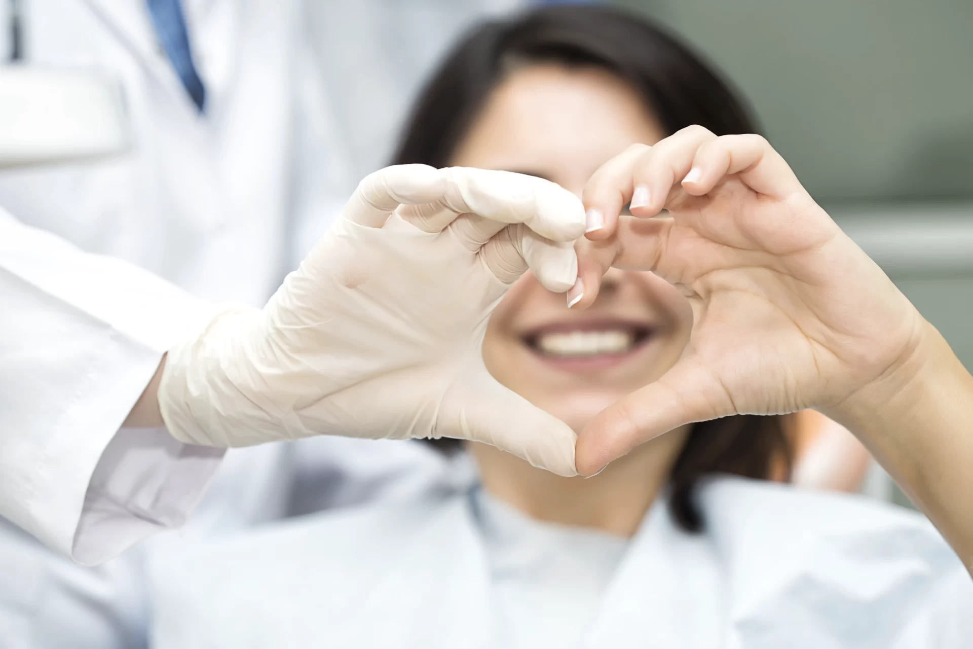 hands making heart formation around dental patient's mouth
