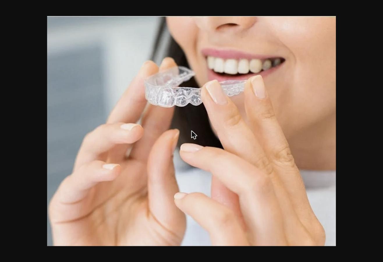 Woman holding a clear dental aligner - Invisalign treatment Fort Lauderdale