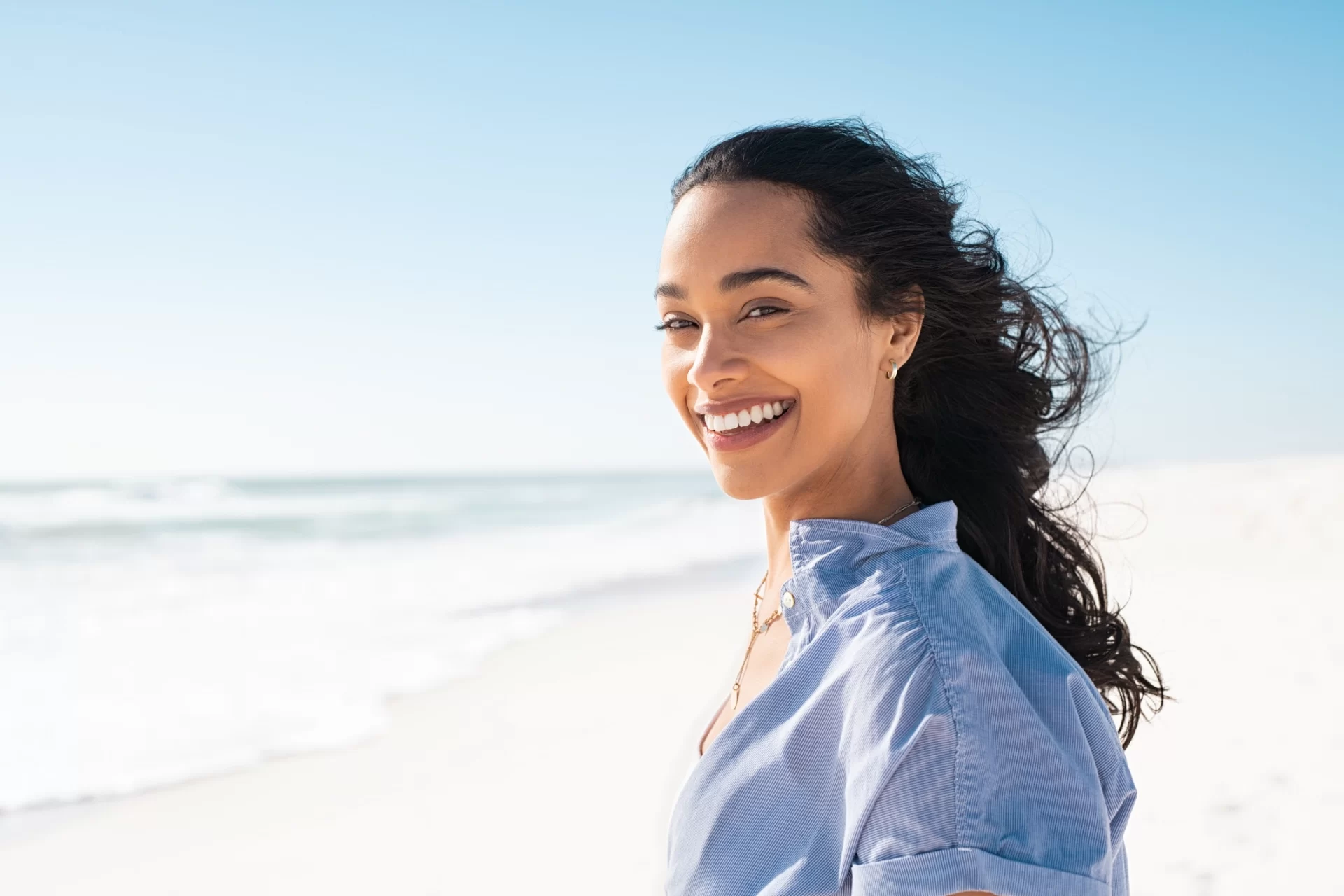 pretty dark haired woman smiling with ocean in background
