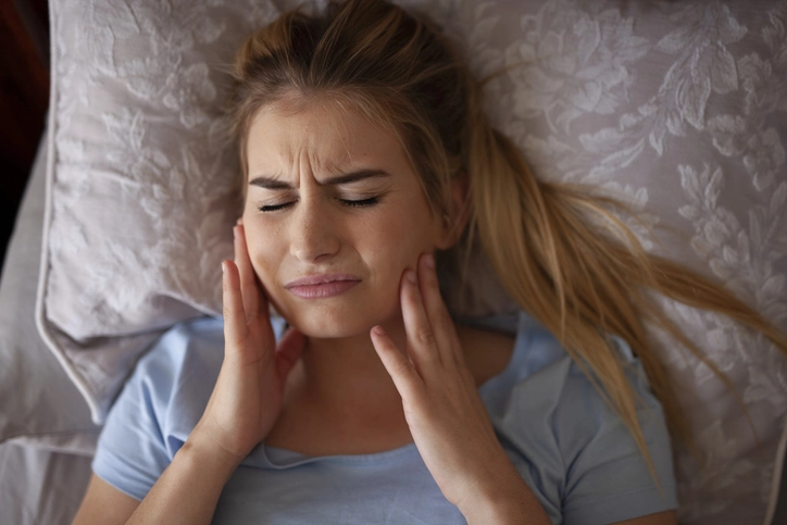 woman holding jaw as if in pain